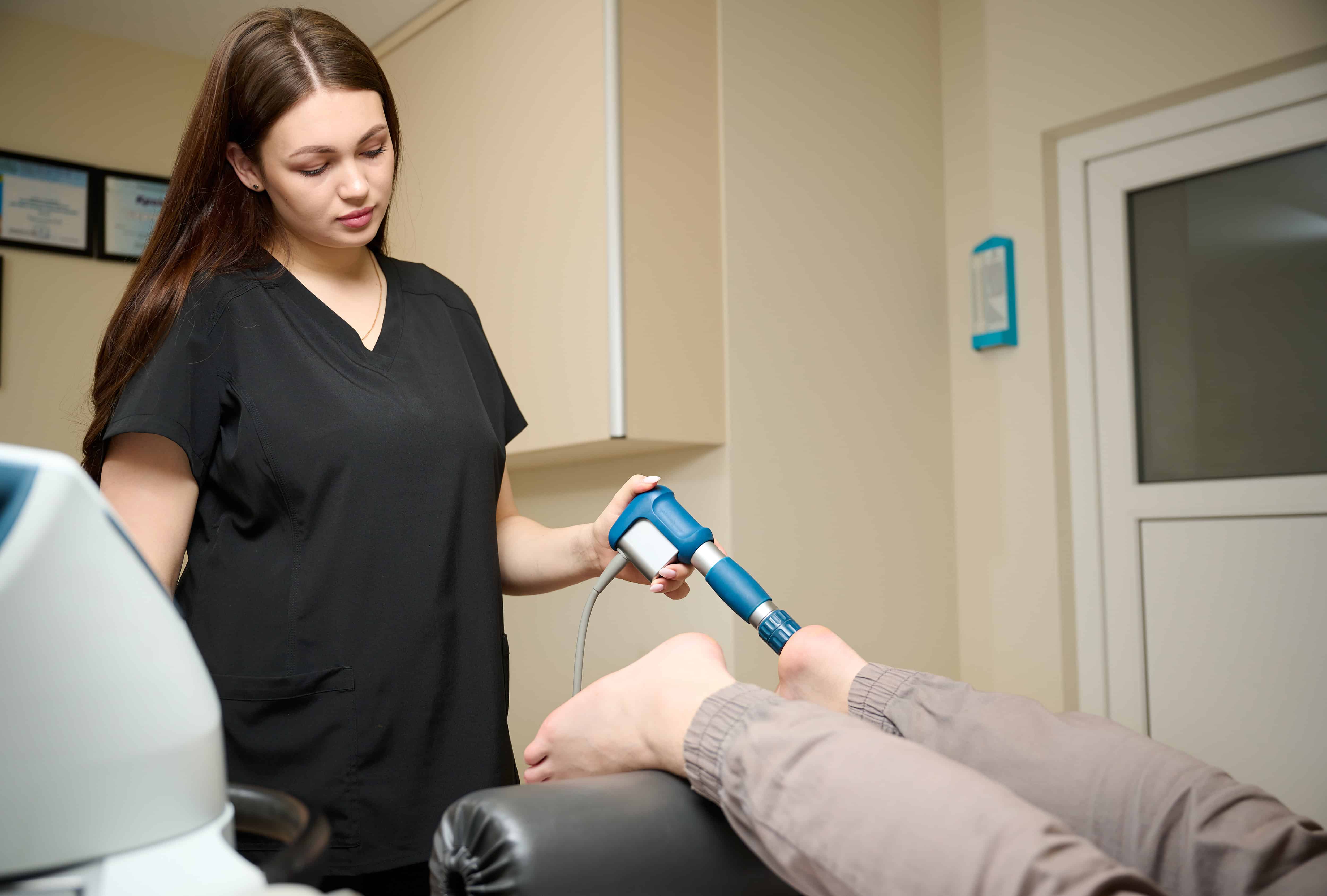 Fizjoterapeuta wykonujący zabieg falą uderzeniową skupioną na stopie