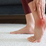 Kobieta trzymająca bolącą piętę - ostroga piętowa i zapalenie rozcięgna podeszwowego